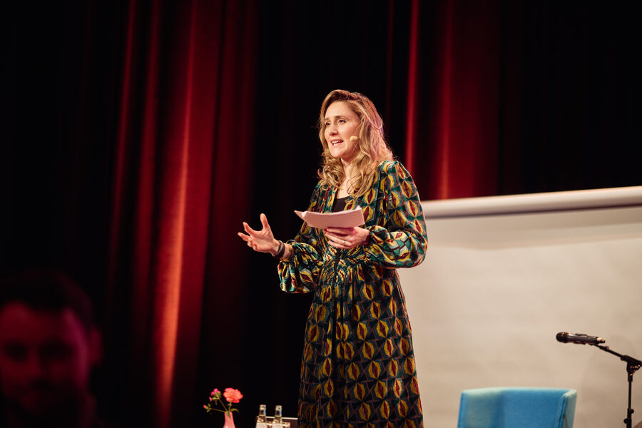 Svea Eckert bei einem Vortrag vor rotem Vorhang